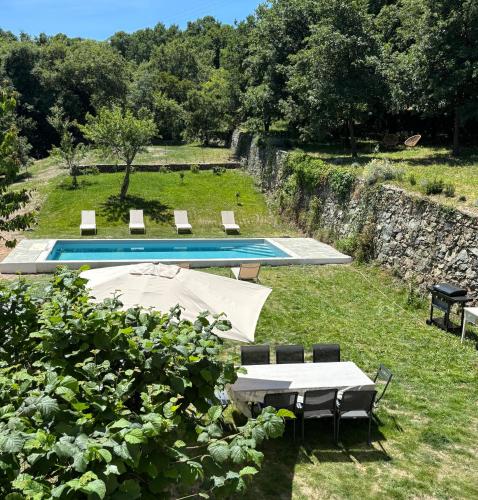 a pool with a table and chairs in the grass at La demeure des vignes in Murato