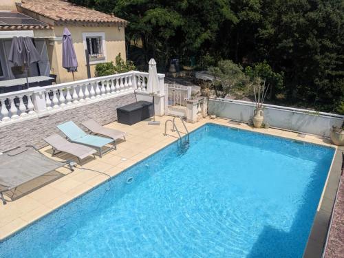 une grande piscine bleue avec deux chaises et une clôture dans l'établissement Villa 3 chambres - Piscine privée sans vis à vis- Idéale 8 personnes, à Les Adrets-de-l'Estérel