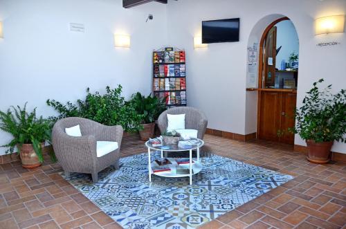 een lobby met 2 stoelen en een tafel op een tegelvloer bij Hostal La Fonda in Conil de la Frontera