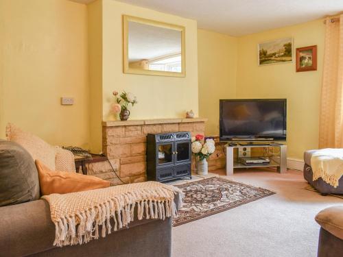 a living room with a fireplace and a tv at Laurel Farm in Rolstone