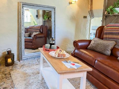 a living room with a leather couch and a table at Cobble Cottage in Instow