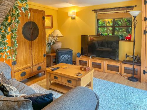 a living room with a television and a table at Yelt Cottage in Wootton