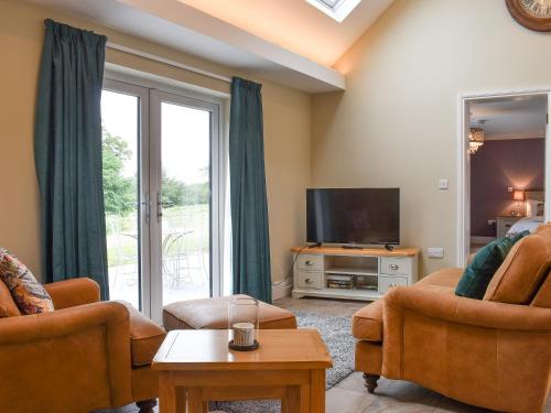 a living room with two chairs and a television at The Cottage At Stainsacre Hall in Hawsker