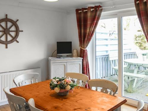 a dining room with a wooden table and a television at Lon Lwyd Isaf in Pentraeth