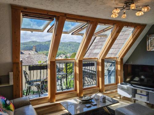 a living room with large windows with a view at Newfold Cottage in Bowness-on-Windermere