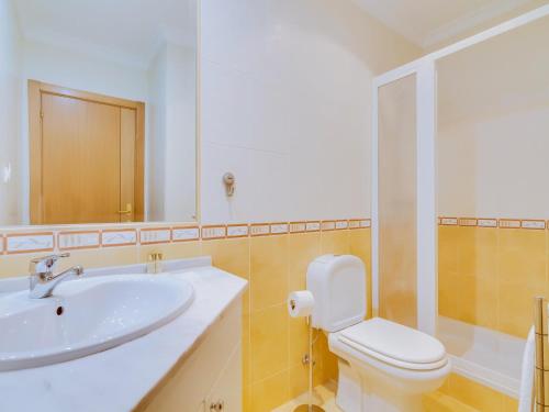Un baño con lavabo, inodoro y espejo. en 1 bdr apartment with pool next to Laguna Golf Course, en Vilamoura