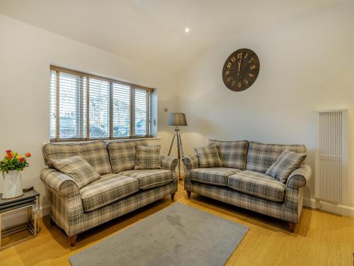 a living room with two couches and a clock on the wall at The Cottage in Langsett