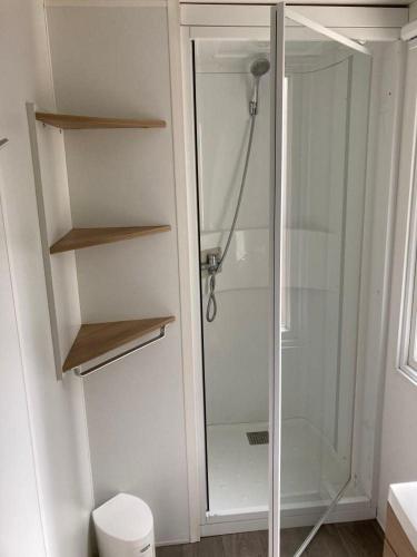 La salle de bains est pourvue d'une douche en verre et de toilettes. dans l'établissement MOBILHHOME 4 à 6 personnes TERRASSE couverte, à Piriac-sur-Mer