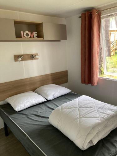 un lit avec deux oreillers dessus dans une chambre dans l'établissement MOBILHHOME 4 à 6 personnes TERRASSE couverte, à Piriac-sur-Mer