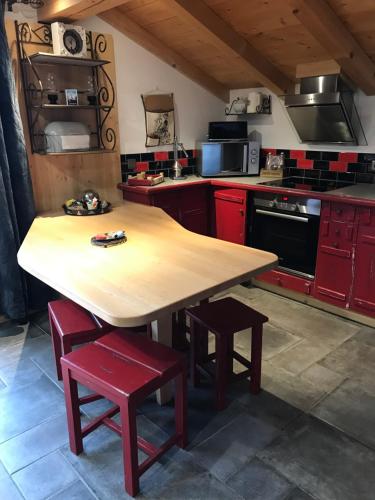 une cuisine avec une table en bois et des placards rouges dans l'établissement Gite Le sommet, à Sallanches