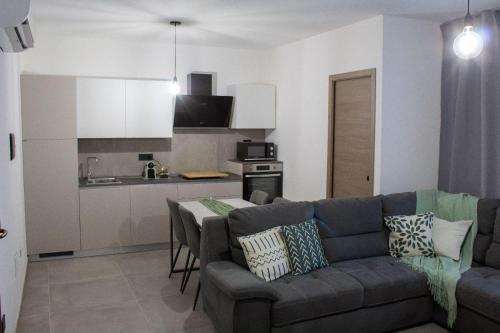 a living room with a couch and a kitchen at Domus Aura Apartments in SantʼAntìoco