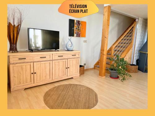un salon avec une télévision sur un meuble en bois dans l'établissement Maison Le Vignoble avec jardin - 6 personnes, à Ribeauvillé
