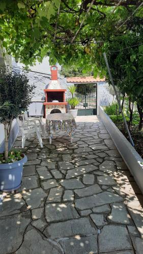 a stone patio with a bench and a fireplace at Vasilis Garden House in Kavala