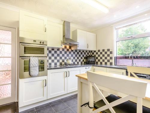 a kitchen with white cabinets and black and white tiles at Manager's Cottage in Loddon