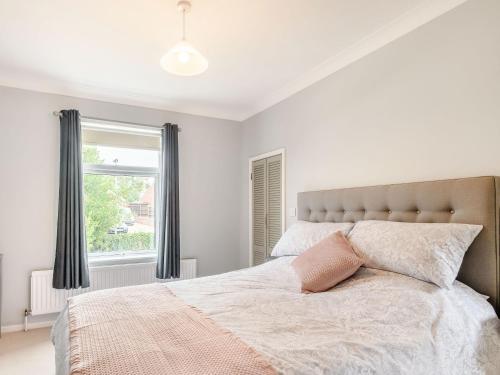 a white bedroom with a large bed with a pink pillow at Manager's Cottage in Loddon