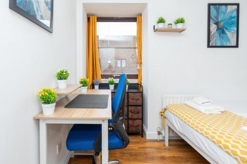 a bedroom with a desk and a bed with blue chairs at Open Mind Property - Cozy 2 Bed Room & Free Parking in Portsmouth