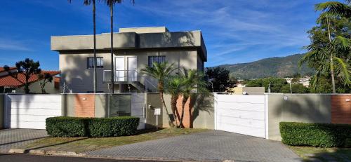 a house with a white fence and palm trees at Apto Inteiro em Atibaia do lado da Av Lucas Bairro Nobre in Atibaia