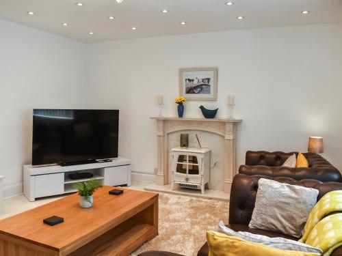 a living room with a couch and a tv and a fireplace at Wylandre in Amlwch