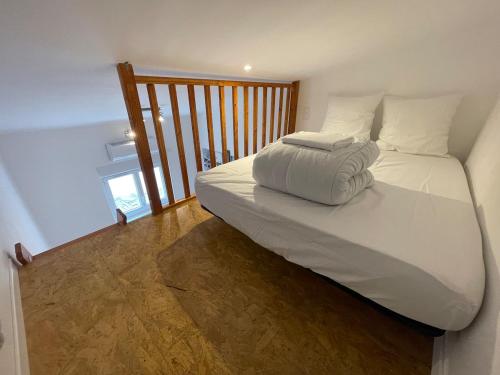 Cette chambre comprend un grand lit blanc et du parquet. dans l'établissement Chez Franou, centre ville , rez de chaussée, à Nîmes
