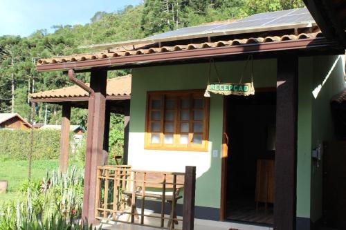 a small house with awning and a table and chairs at Chalés Verde Maua in Visconde De Maua