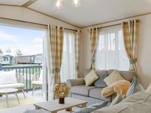 a living room with a couch and a balcony at Pinecone Lodge in Sherburn
