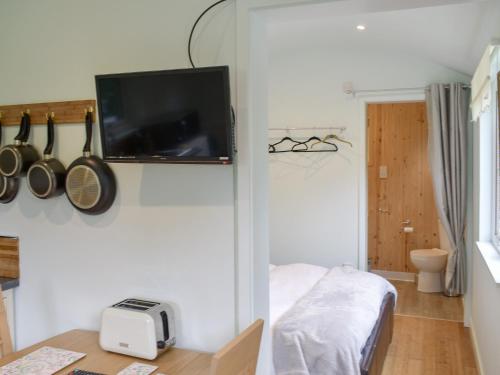a room with a tv on a wall with a bed at Shepherds Hut 3 At Laddingford - Uk32532 in Yalding