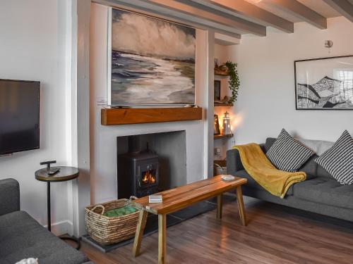 a living room with a couch and a fireplace at Seren Cottage By The Sea in Bodorgan