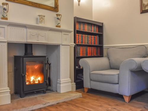 a living room with a fireplace and a chair and book shelf at Rascal's Rest in Whitby
