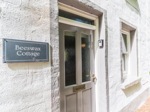 a door with a sign on the side of a building at Beeswax Cottage in Dalton in Furness