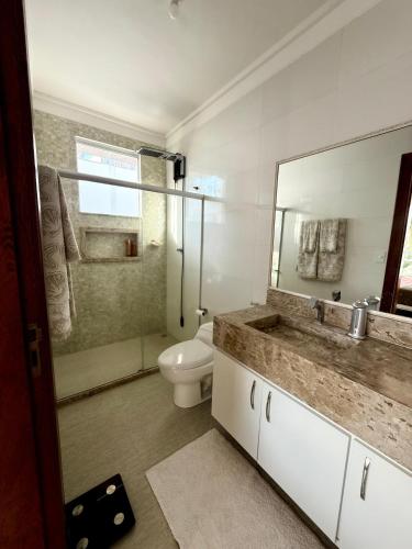 a bathroom with a toilet and a sink and a mirror at Mansão 04 Quartos com piscina privativa in Porto Seguro