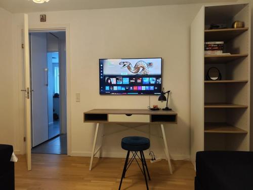 a computer desk with a monitor and a stool in a room at Cozy villa apartment close to everything in Hørning