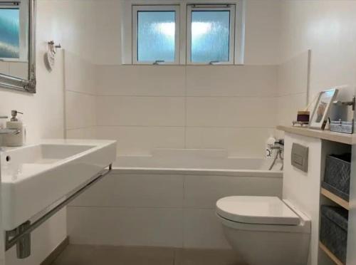 a white bathroom with a toilet and a sink at Cozy villa apartment close to everything in Hørning