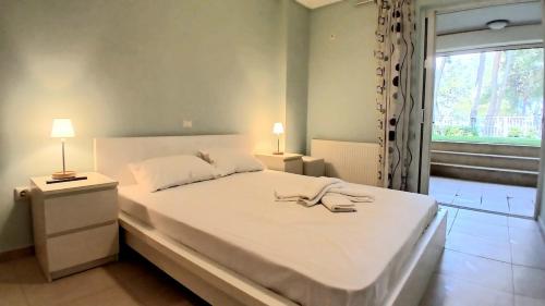 a bedroom with a large white bed with a window at Vila Irida in Nea Makri