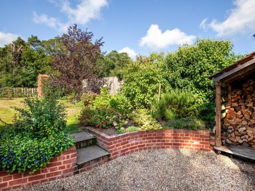 a garden with a brick wall and a bench at Colbridge Cottage in Docking