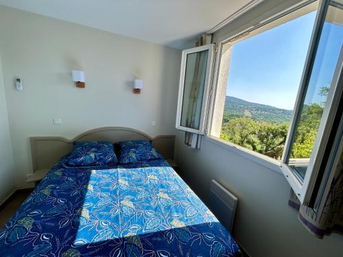 una camera da letto con un letto e una grande finestra di Les Restanques vue mer Freesia a Grimaud