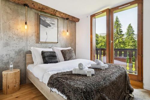 une chambre avec un grand lit et une grande fenêtre dans l'établissement KAZA BELLA Les Carroz Chalet moderne avec vue Duplex 3 chambres et 3 SDB Les Carroz Grand Massif, à Arâches-la-Frasse