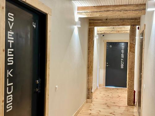 a hallway with a black door and wooden floors at Svētes klubs 