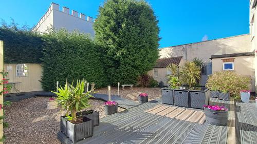 a garden with a wooden deck with plants and a tree at The East Wing at Rufford Park Lodge, Hot Tub Retreat in Edwinstowe