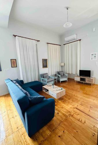 a living room with a blue couch and wooden floors at Messenian Style House with Great Views in Petalidhion