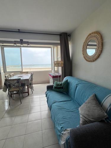 un salon avec un canapé bleu et une table dans l'établissement Appartement lumineux en front de mer, à Frontignan