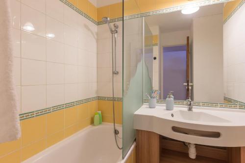 uma casa de banho com um lavatório e uma banheira em Résidence Pierre & Vacances Les Sentiers du Tueda em Méribel