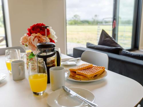 a table with a plate of breakfast food and orange juice at 2 Bed in Sturminster Newton 88265 in Fiddleford