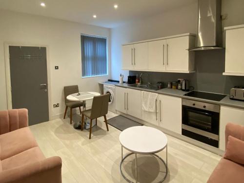 a kitchen with white cabinets and a table and chairs at New York Apartment in Sheffield