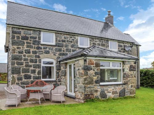 a stone house with a table and chairs outside at Plas Madog in Llanuwchllyn