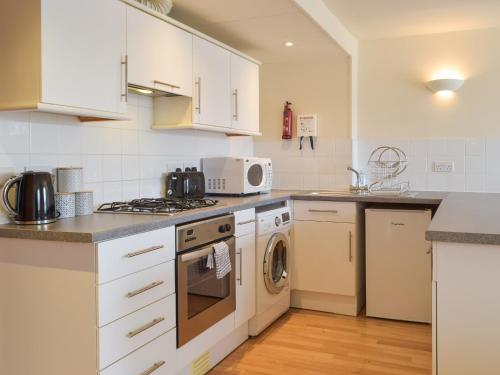 a kitchen with white cabinets and a washer and dryer at Sovereign House in Milford Haven