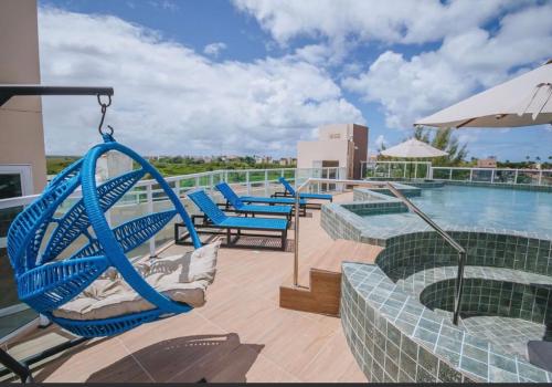 eine Terrasse mit Stühlen und einer Schaukel neben einem Pool in der Unterkunft Flat Porto de Galinhas in Porto De Galinhas