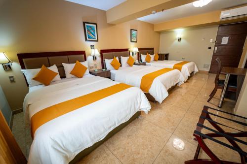 a hotel room with two beds with orange and white sheets at Gran Recreo Hotel - Trujillo - Perú in Trujillo