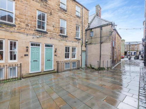 an empty courtyard in front of a brick building with blue doors at Town Square Apartment - Uk45611 in Alnwick