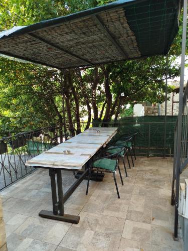 a large wooden table with chairs under an umbrella at Serenita Stone House in Becici