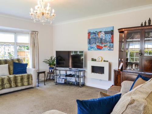 a living room with a couch and a tv at Corner Cottage in Sewerby